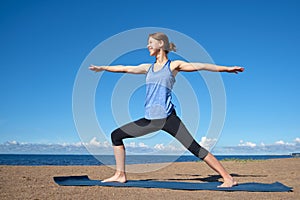 Young slim girl doing yoga on the beach on a sunny morning