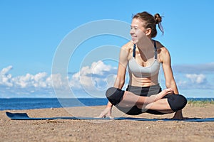 Young slim girl doing yoga on the beach on a sunny morning, positive attitude, healthy lifestyle