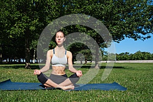 Young slim girl doing yoga, lotus position, relaxation and meditation