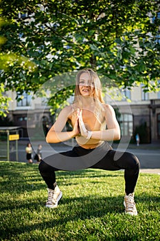 Young slim pretty girl doing yoga on grass in summer park at sunset.