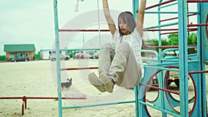 young slim sporty brunette woman doing ABC exercises for core musculs by lifting legs while hanging on horizontal bar on