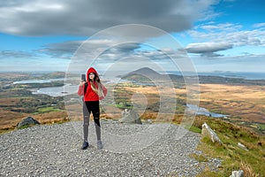 Young slim teenager girl model on a hike to Diamond hill taking selfie on her smart phone, Connemara National park, Letterfrack,