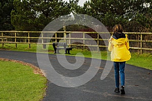 Young slim teenager girl in yellow jacket in walking on a footpath in a zoo park. Outdoor acitivity