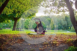 Young slim woman doing yoga and stretching, fitness exercises in sunny green forest  park