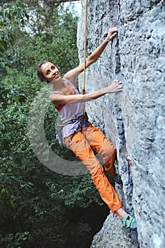 Young slim woman rock climber climbing on the cliff
