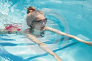 Young slim woman in swimsuit relaxing by swimming pool