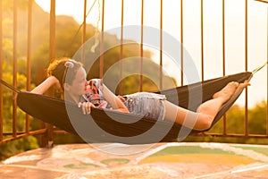 Young slim woman in tropical exotic hammock sunset lights