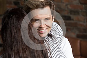 Young sly liar man happily smiling while woman embracing him photo