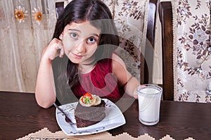 Young small beautiful middle eastern child girl with chocolate cake with pineapple, strawberry, and milk with red dress and dark