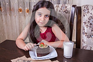 Young small beautiful middle eastern child girl with chocolate cake with pineapple, strawberry, and milk with red dress and dark