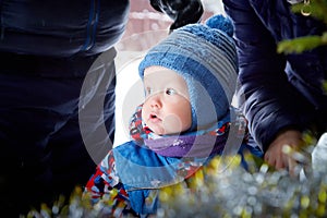 Young small boy walking and having photo shoot in park or forest full of snow in a cold winter day. Male child having