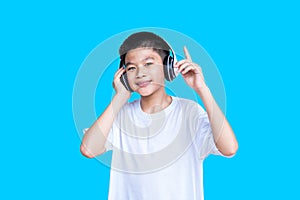 Young smart Asian boy close his eyes with white headphones isolated on skyblue background.