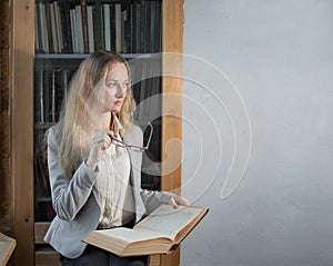 A young smart intelligent woman sits with a book in her hands