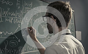 Young smart mathematician drawing on the chalkboard