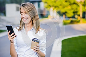 Young smart professional woman reading using phone. Female businesswoman reading news or texting sms on smartphone