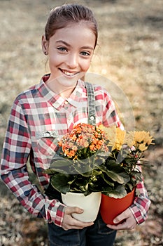 Young smart schooler taking plants in colorful plant