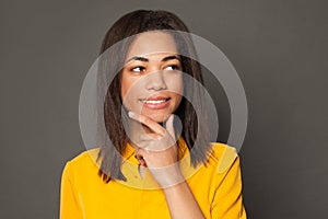 Young smart woman brunette thinking and smiling on gray background