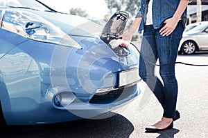 Young smart woman standing and using charging gadget.