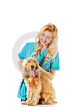 Young smile female veterinarian examinng dog