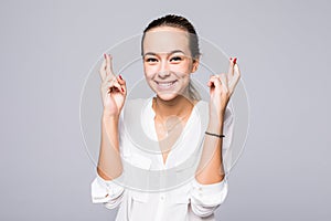 Young smile woman keeps fingers crossed, hopes for good luck, isolated against gray background with copy space