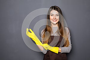 Young smile woman wearing rubber gloves on grey background
