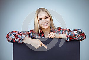 Young Smileing teenager blond girl hold black blank paper and shows on it.