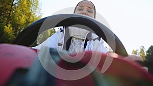 Young smiles beautiful woman driving ATV, through the sun, hands hold steering wheel in slowmotion. 1920x1080