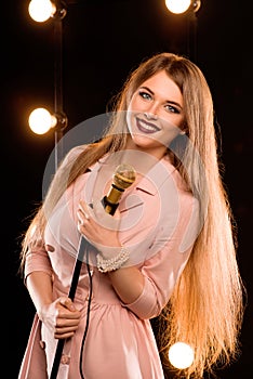 Young smiley beautiful long hair girl with microphone singing
