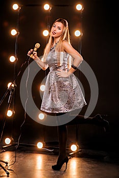 Young smiley beautiful long hair girl with microphone singing song