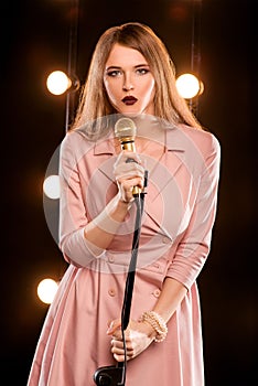 Young smiley beautiful long hair girl with microphone singing song