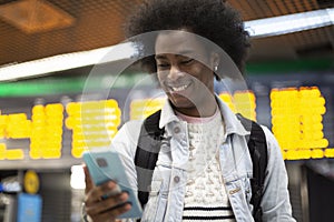 Young smiling African American man using his mobile phone at the airport