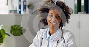 Young smiling African-American woman doctor sitting in clinic office.