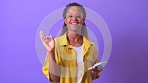 Young smiling African American woman with phone and demonstrating OK gesture