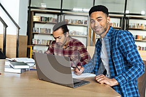 Young smiling african male student using laptop for a study