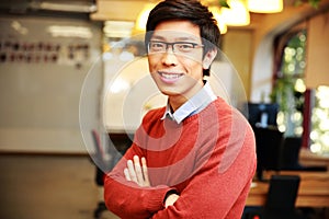 Young smiling asian man with arms folded