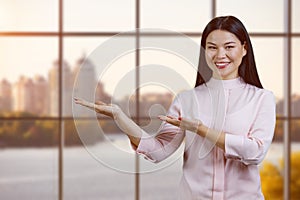 Young smiling asian woman holding copy space on her palms.