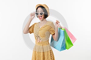 Young smiling asian woman holding multi coloured shopping bags and looking on white background