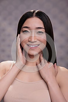 Young smiling asian woman touching fresh glowing skin