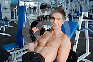 Young smiling athlete lifting weights in the gym