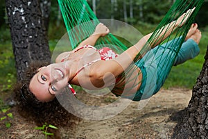 Young smiling barefooted woman swing in hammock