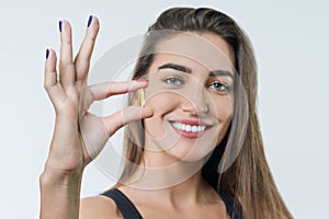 Young smiling beautiful healthy woman in sportswear with vitamin D, E, A fish oil omega-3 capsules, on white background