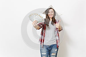 Young smiling beautiful woman in newspaper hat holding bundle of dollars, cash money and showing thumb up isolated on