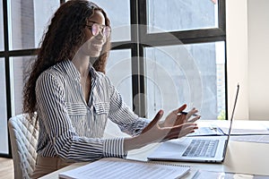 Young smiling black businesswoman at desk having online meeting using laptop.
