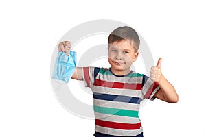 Young smiling boy taking off medical protective mask and shows thumbs up. covid-19 pandemic, self-isolation concept