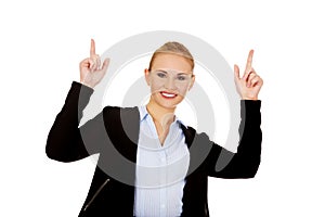 Young smiling business woman pointing up