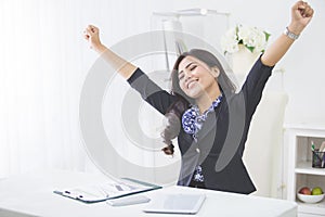 Young smiling business woman raise arm after finishing her work