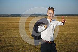 A young smiling businessman goes with his indexed finger up. It symbolizes attention. Be vigilant