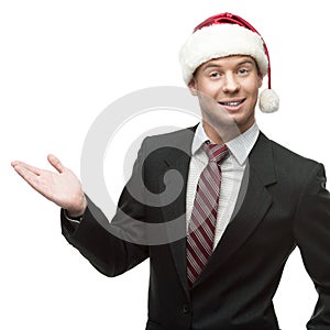 Young smiling businessman in santa hat showing empty space