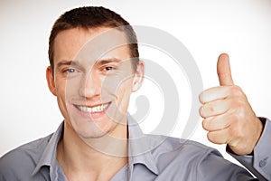 Young smiling businessman showing thumb up