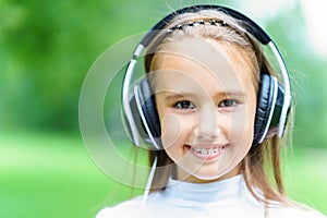 Young smiling caucasian girl listening music with professional DJ headphones and getting fun